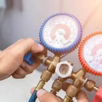 AirMaster technician using HVAC pressure gauges during service