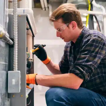 Technician inspecting HVAC unit with tools